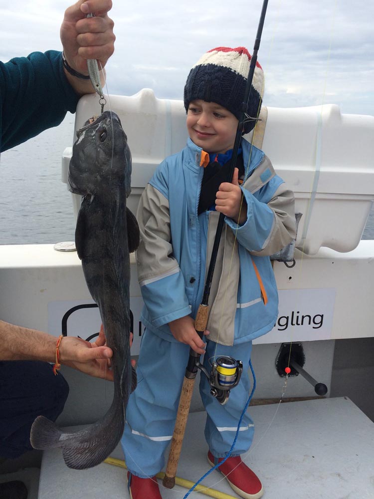 Young fishermen with his freshly caught catfish and a frighten look on his face